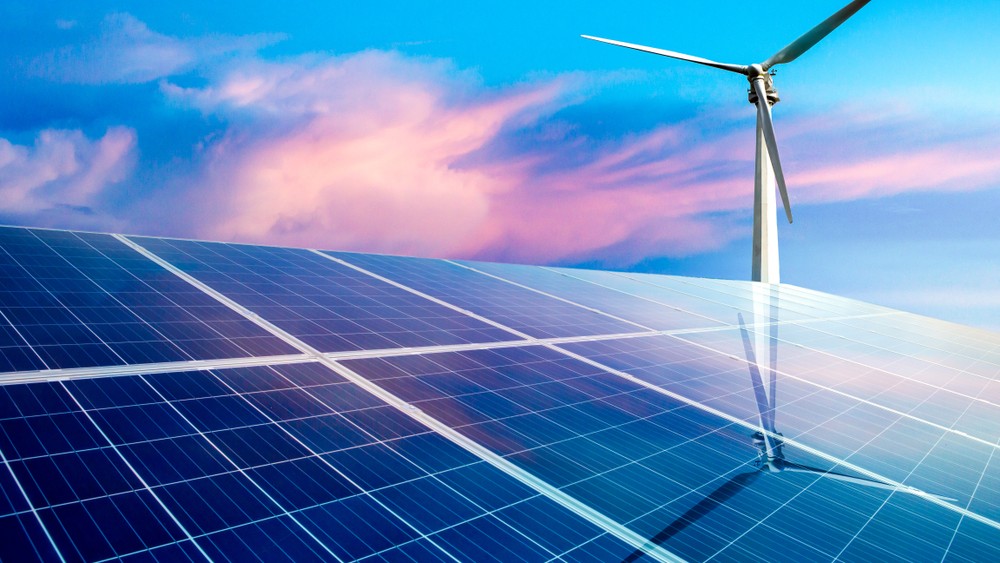 Solar panels and wind turbines in a landscape, representing renewable energy.